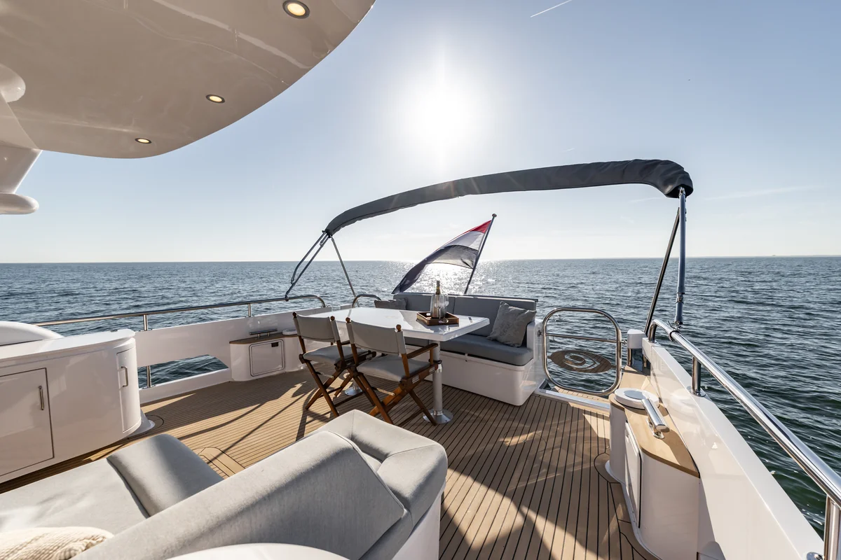 Elling E6 aft deck with upholstered seating, a table, teak decking and open sea beyond.